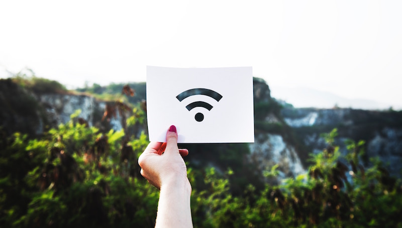 Photo of a WiFi sign in front of a background of rocks and trees.