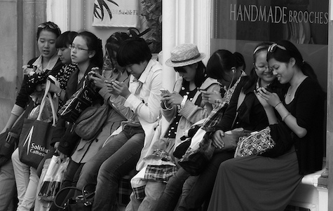 Photo: byronv2 (Flickr, CC BY-NC 2.0) A group of women rest on a window ledge, looking at their phones.