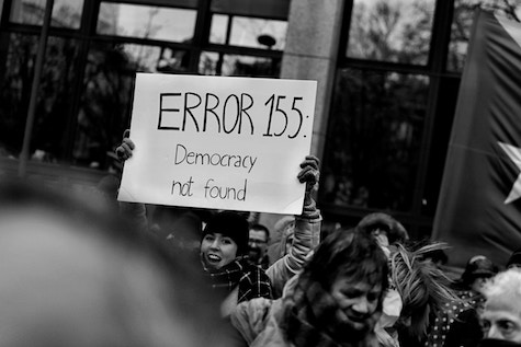 Person at a rally is holding a sign that reads 